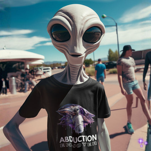 Alien wearing a t-shirt with an alien graphic and 'Abduction Enjoyer' text on a street.
