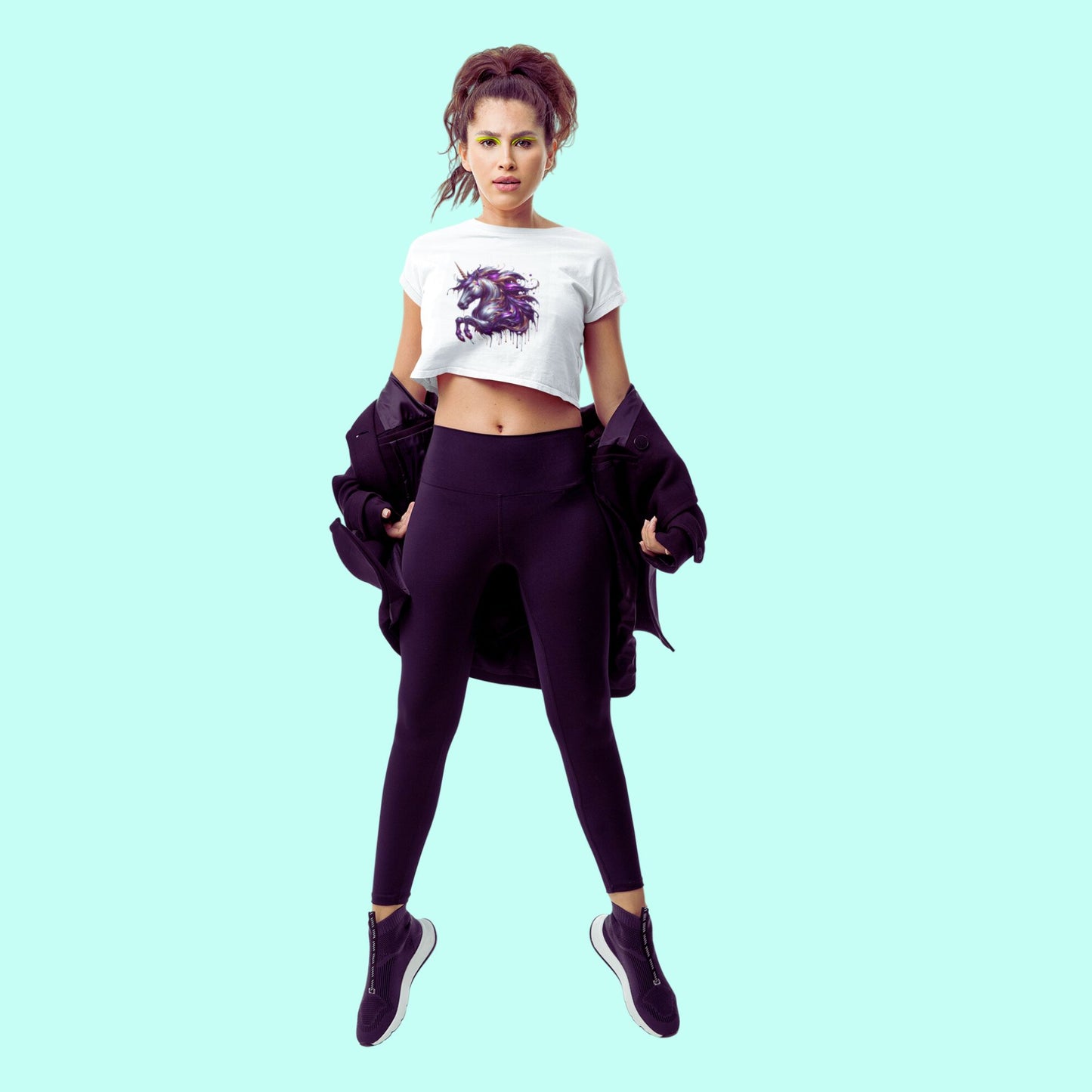 Melting Unicorn crop top in white, made from organic cotton. Female model jumping up in a studio setting while showcasing the crop top.