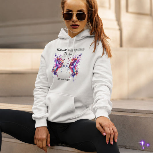 Woman wearing a white hoodie with colorful graphic and text, sitting on steps.