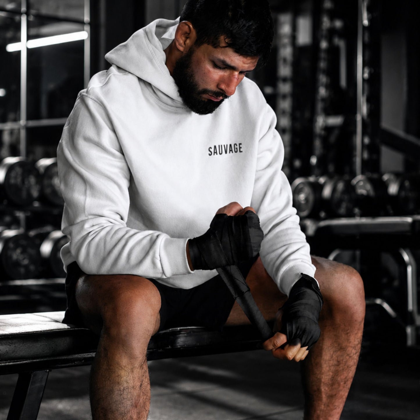 Person in a gym wearing a 'SAUVAGE' hoodie, preparing for a workout.