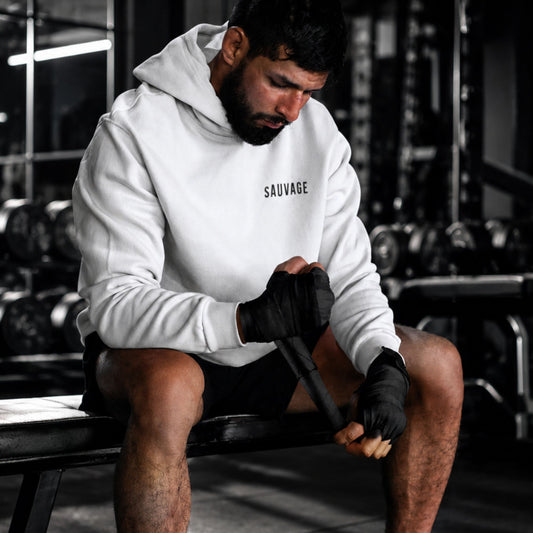 Person in a gym wearing a 'SAUVAGE' hoodie, preparing for a workout.