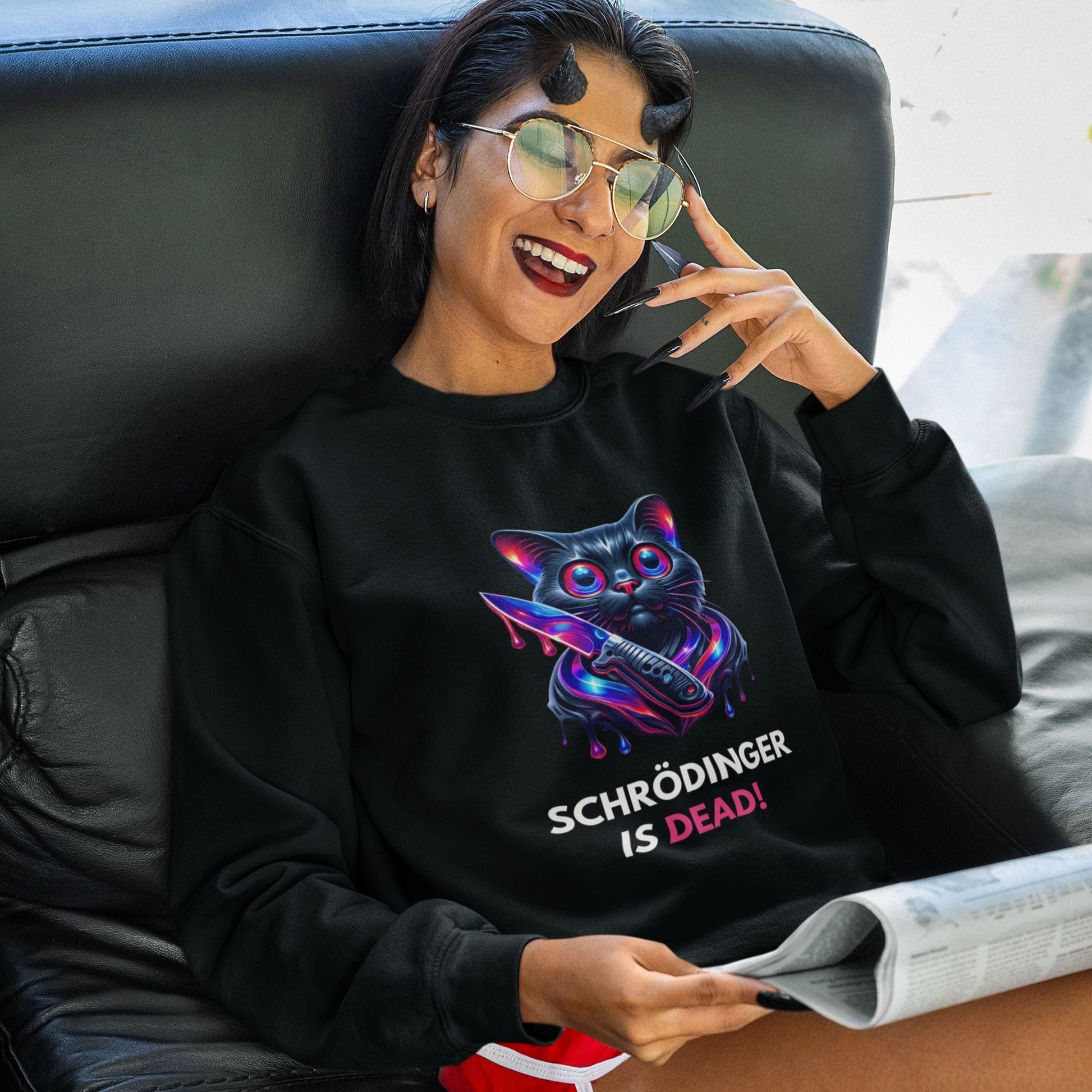 Schrödinger is dead Black Cat Sweatshirt in black, made from organic cotton. Female model reading a newspaper wearing the sweatshirt.