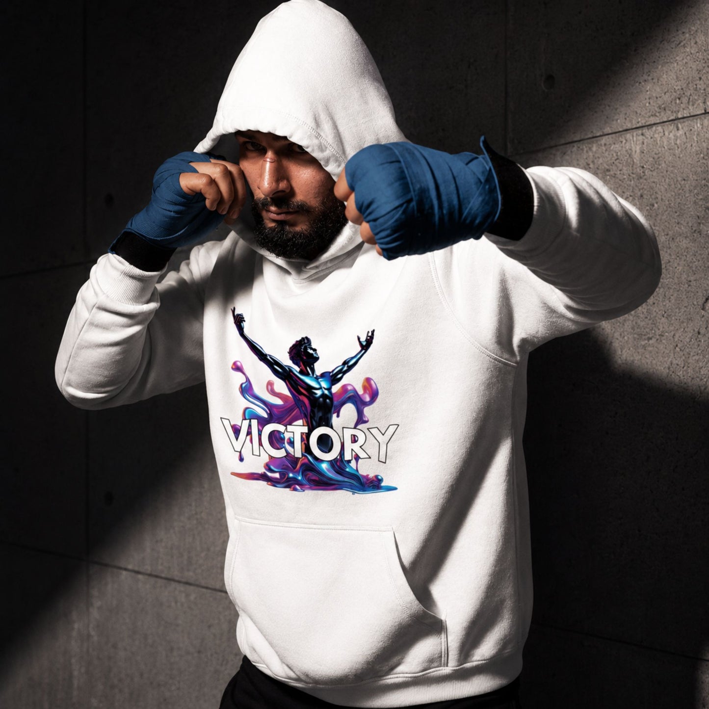 Person wearing a white hoodie with 'VICTORY' design and blue boxing gloves against a dark brick wall.