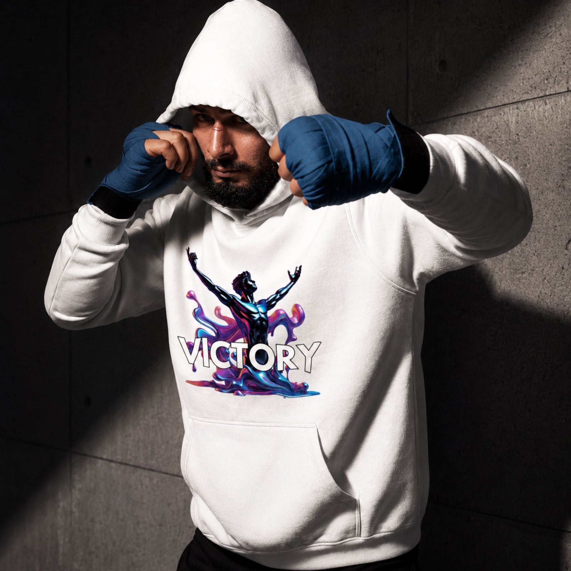 Person wearing a white hoodie with 'VICTORY' design and blue boxing gloves against a dark brick wall.