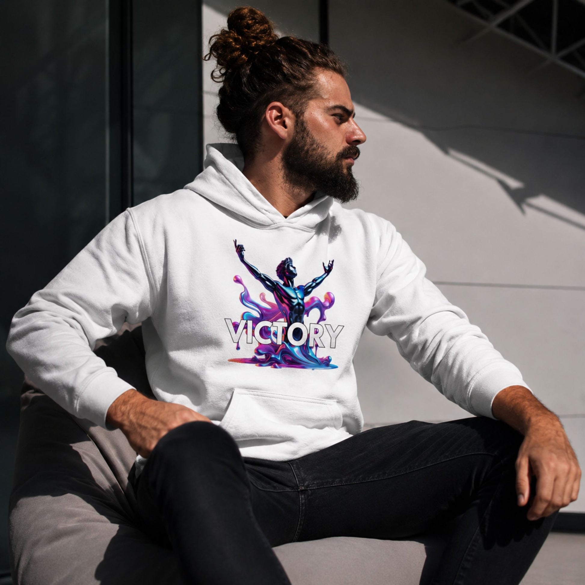 Man wearing a white hoodie with 'VICTORY' design sitting outdoors.