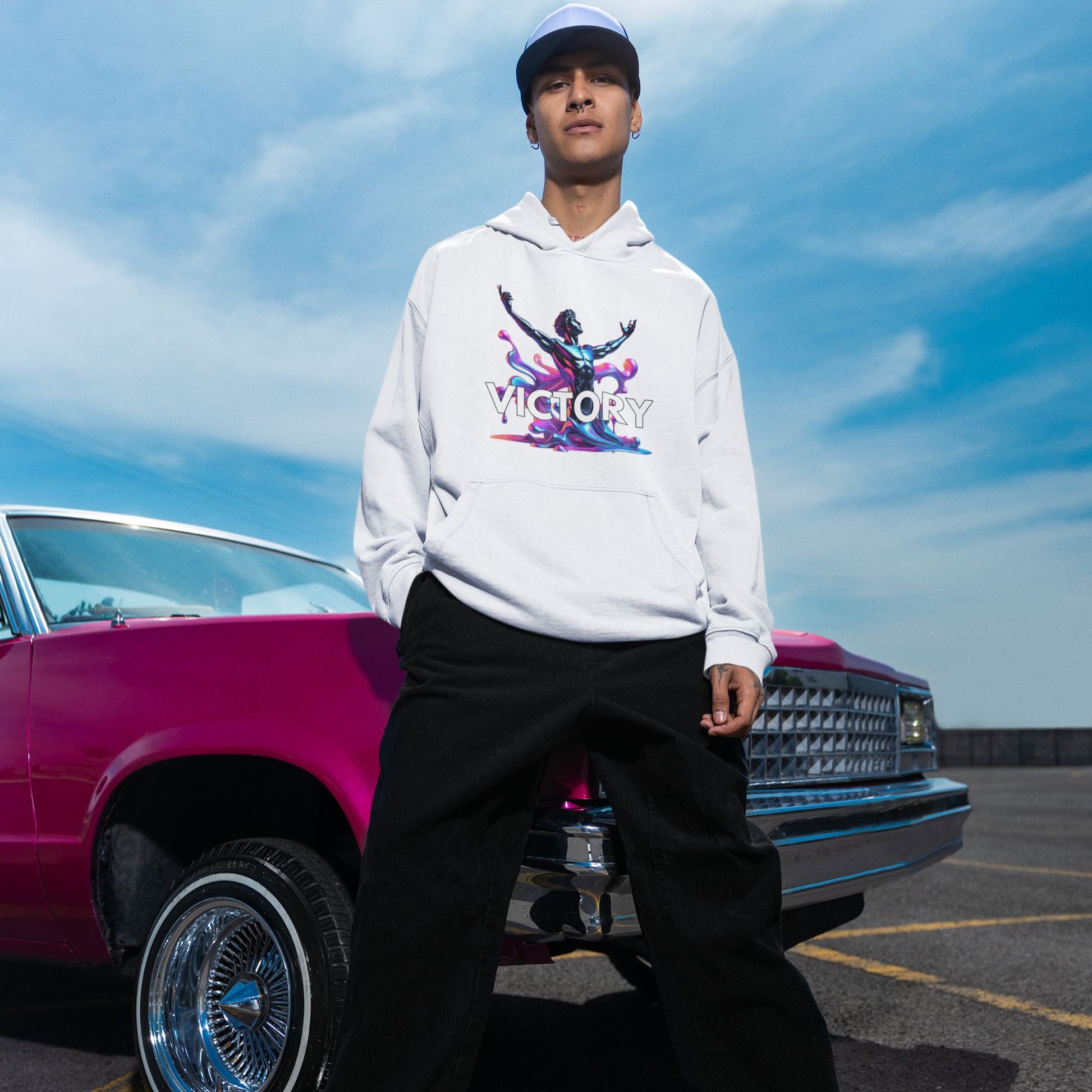 Victory Hoodie in white, made from organic cotton. Male model showcasing hoodie in a lifestyle setting in front of a pink car.