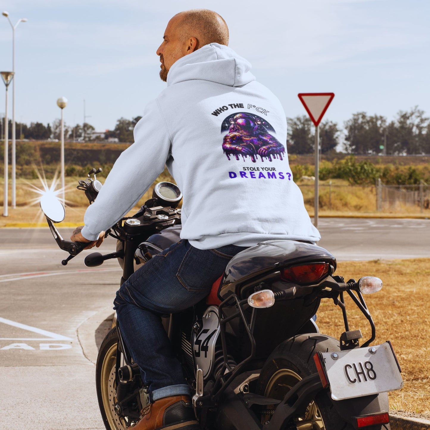 Who the F*ck stole your dreams Hoodie in white, made from organic cotton. Male model on a motorcycle showcasing hoodie from the back.